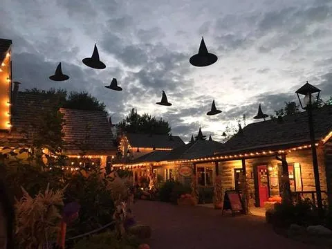 Witch hats hovering over the lantern-lit lanes of Gardner Village at dusk during WitchFest