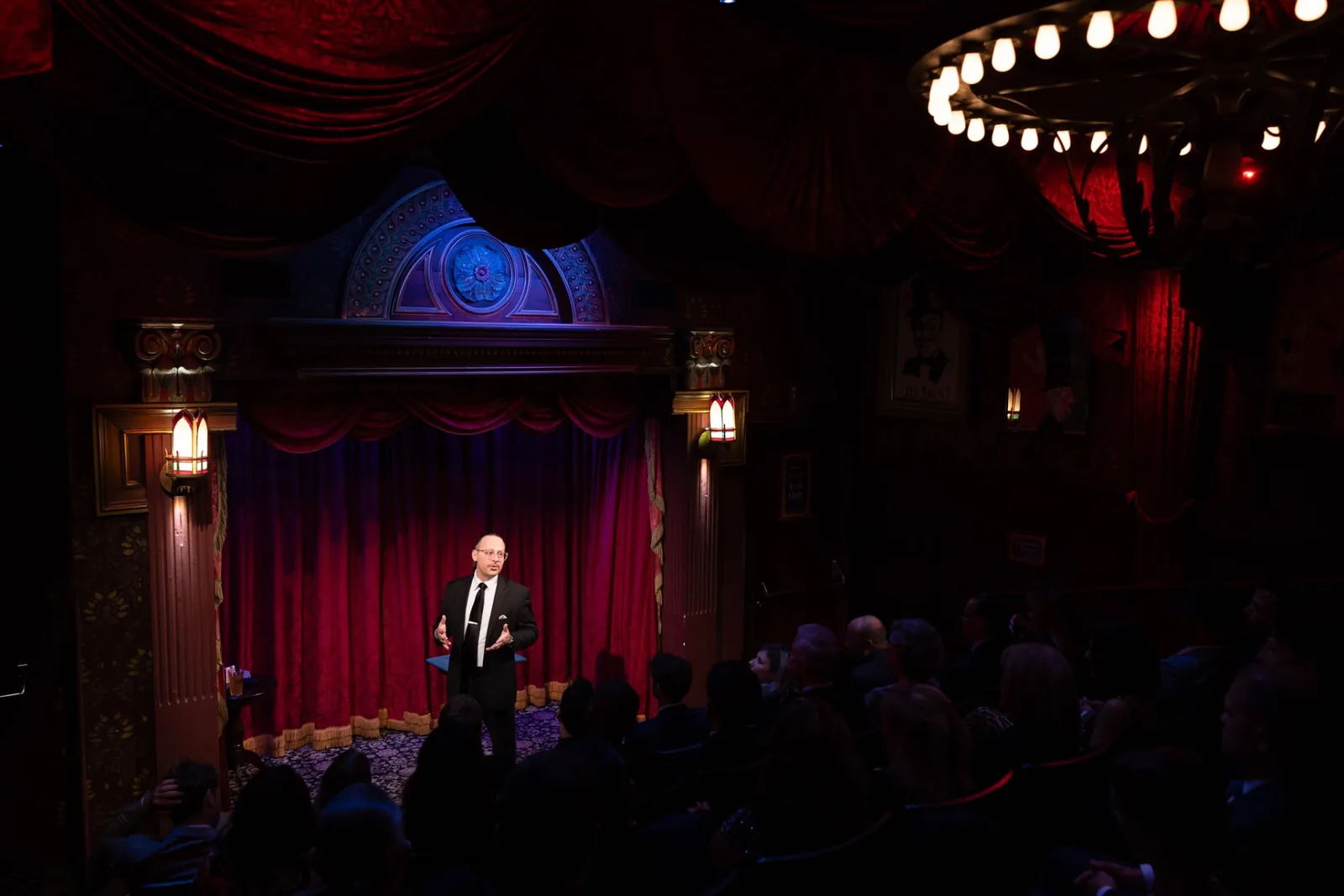 A magician alone in the spotlight before a full house in the Prestige theatre